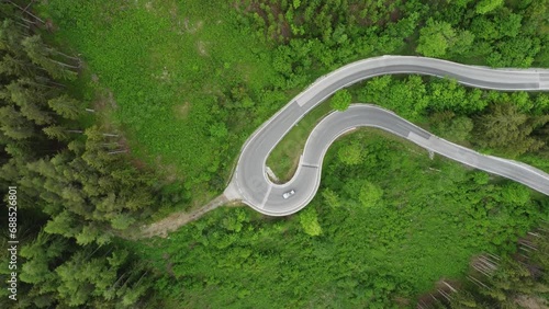 4K overhead drone shot of cars driving on a winding serpentine road. Route between Schladming and Ramsau am Dachstein, near Dachstein Glacier. Beautiful pine trees and alpine nature photo