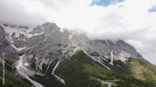 4K drone shot of majestic Dachstein Glacier, Styria, Austria in the Alps. Popular area for Alpine and cross-country skiing, snowboarding. Huge rock formations overlook lush green fields. photo