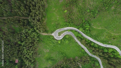 4K overhead drone shot of cars driving on a winding serpentine road. Route between Schladming and Ramsau am Dachstein, near Dachstein Glacier. Beautiful pine trees and alpine nature photo