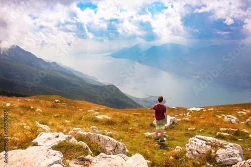 Hiker looking at panoramic view of lake Garda from a mountain photo