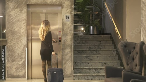 Blonde Business Woman entering the elevator with suitcase photo