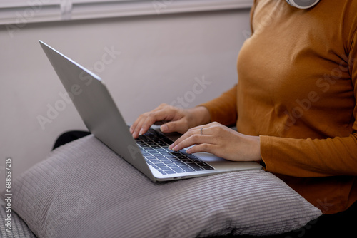 Beautiful young woman with laptop resting on couch at home 