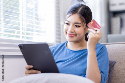 Mobile Shopping. Cheerful Asian Woman Using Smartphone Shopping Online Holding Credit Card Making Payment Sitting At Sofa At Home. Internet Banking Application And E-Commerce  © David