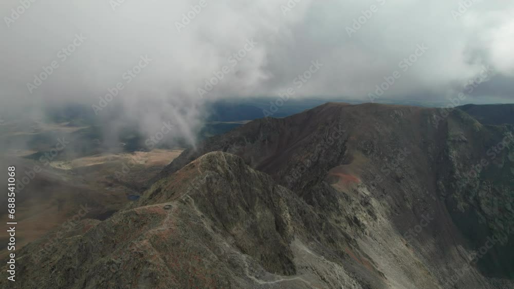 Aerial view of the Carlit mountain peak with moving clouds during autumn in the French Pyrenees. Aerial view of the Carlit mountain peak with moving clouds during autumn in the French Pyrenees.