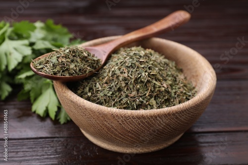 Dried aromatic parsley and fresh leaves on wooden table, closeup