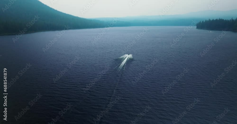 Aerial rear view follows speed boat wake across open deep blue mountainous lake Aerial rear view follows speed boat wake across open deep blue mountainous lake
