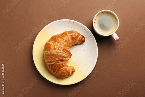 Fototapeta Naklejka Na Ścianę i Meble -  Delicious fresh croissant and cup of coffee on brown table, flat lay