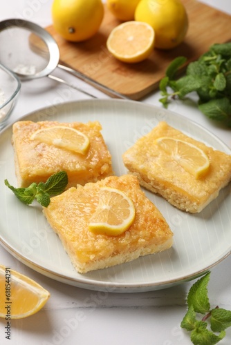 Tasty lemon bars and mint on white table