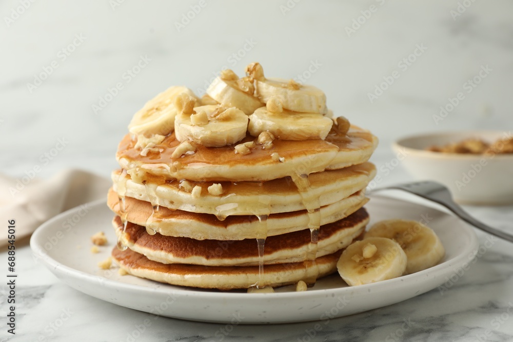 Delicious pancakes with bananas, walnuts and honey on white marble table, closeup Delicious pancakes with bananas, walnuts and honey on white marble table, closeup