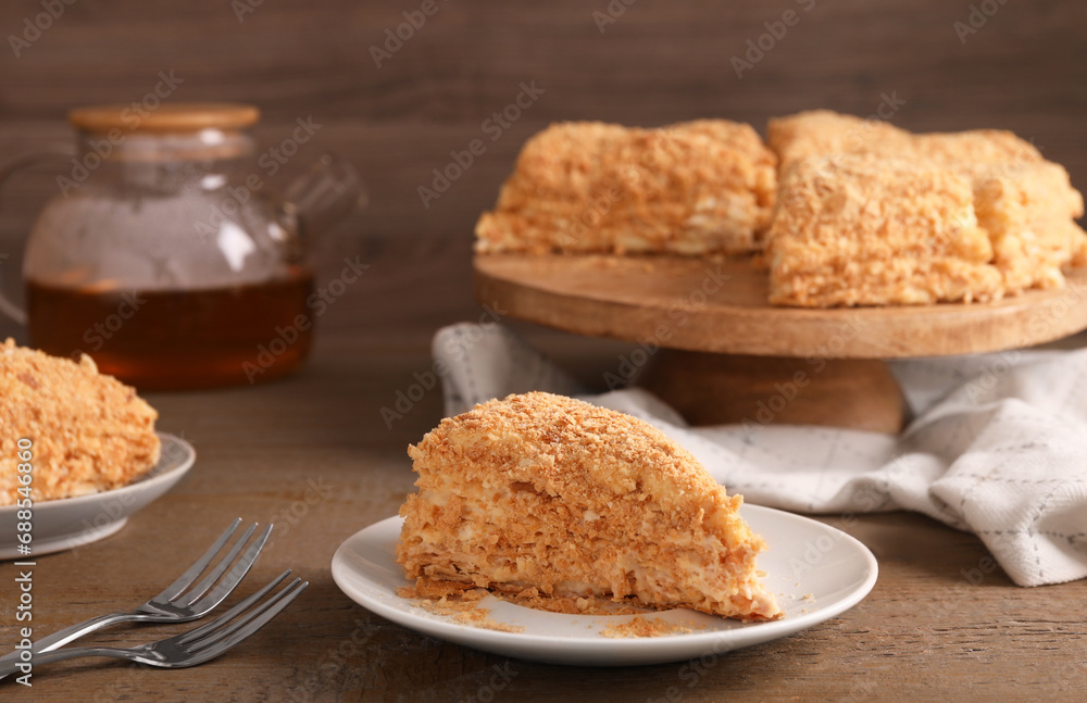 Piece of delicious Napoleon cake served on wooden table, closeup