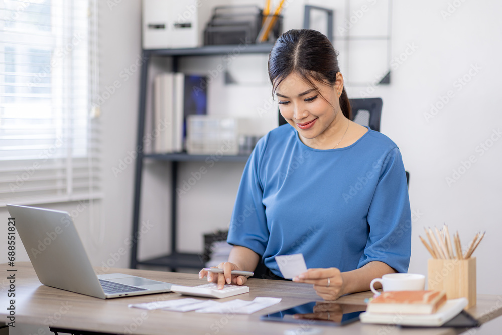 asian woman using calculator and calculate bills in home office. tax form us business income office Financial document. Tax time.Tax concept. asian woman using calculator and calculate bills in home office. tax form us business income office Financial document. Tax time.Tax concept.