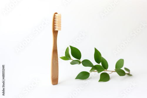 Ecological bamboo toothbrush and fresh green leaves on a white background. The concept of dental care and the use of environmentally friendly materials to create a brush.