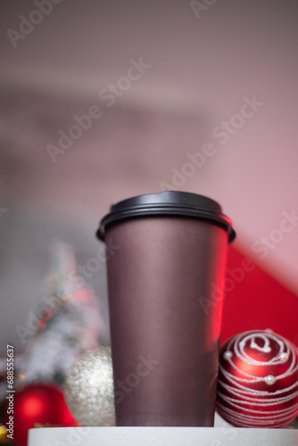 Brown disposable glass with coffee and New Year decorations. Hot Christmas drink in a mug. Coffee to go, delivery. New Year promotion, advertising, background