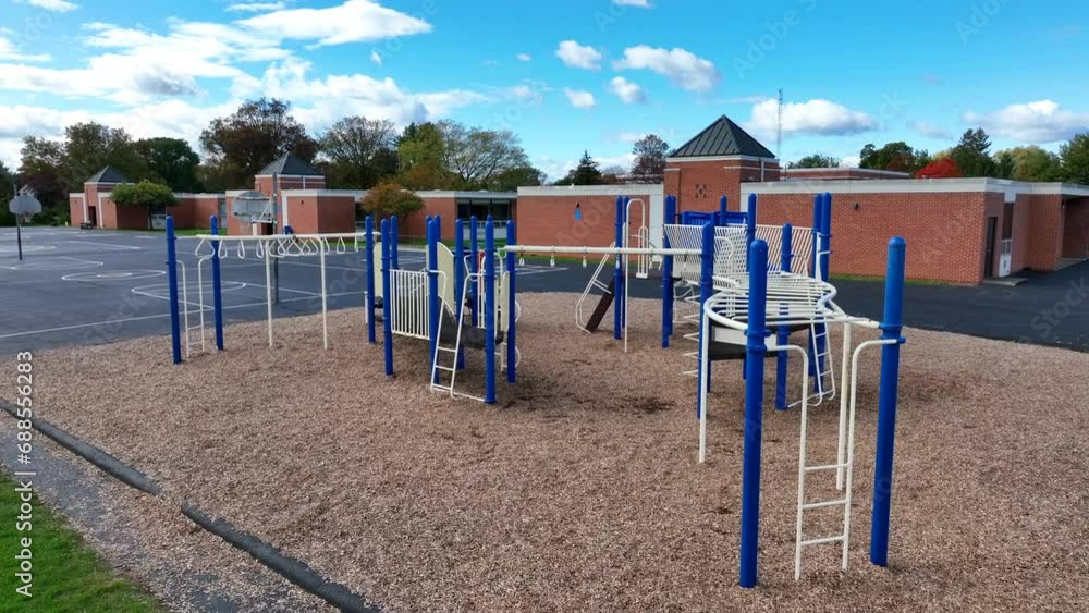 Playground with blue and white equipment on wood chips, next to a school and basketball court. Playground with blue and white equipment on wood chips, next to a school and basketball court.