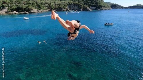  Adventurous young man jumping off a cliff does a backflip in Greece