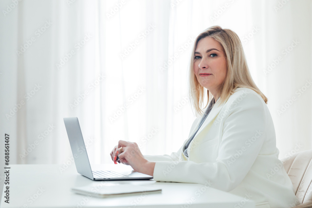 works online on a laptop computer, prints text to a project partner. The student manager is sitting on a chair works online on a laptop computer, prints text to a project partner. The student manager is sitting on a chair