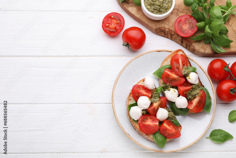 Delicious Caprese sandwiches with mozzarella, tomatoes, basil and pesto sauce on white wooden table, flat lay. Space for text Delicious Caprese sandwiches with mozzarella, tomatoes, basil and pesto sauce on white wooden table, flat lay. Space for text
