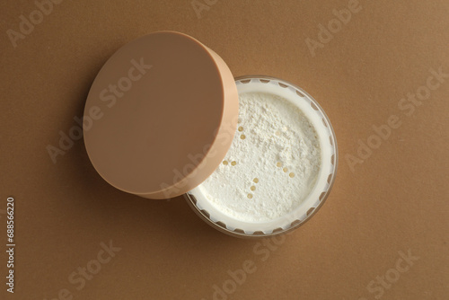 Rice loose face powder on brown background, top view. Makeup product