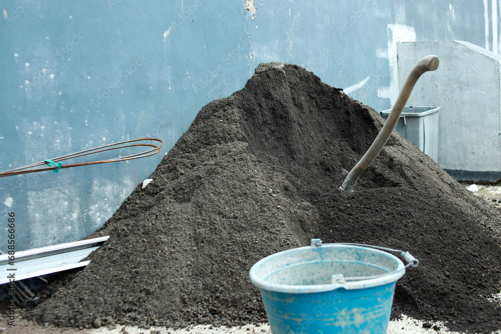 Mound of grey sands with hoe and a bucket for home renovation