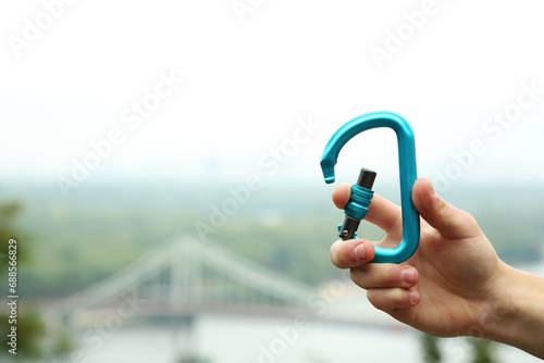 Vászonkép Man holding metal carabiner outdoors, closeup. Space for text