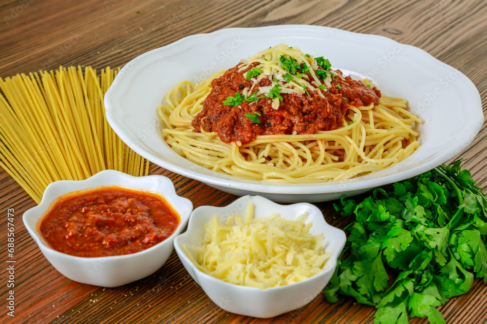 Spaghetti bolognese pasta with chili sauce paste and coriander served in dish isolated on table side view of arabic food Spaghetti bolognese pasta with chili sauce paste and coriander served in dish isolated on table side view of arabic food