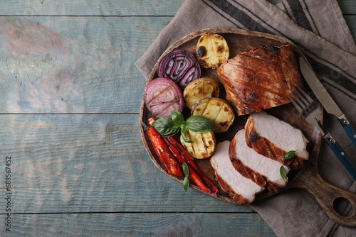 Delicious grilled meat and vegetables served on wooden table, top view. Space for text