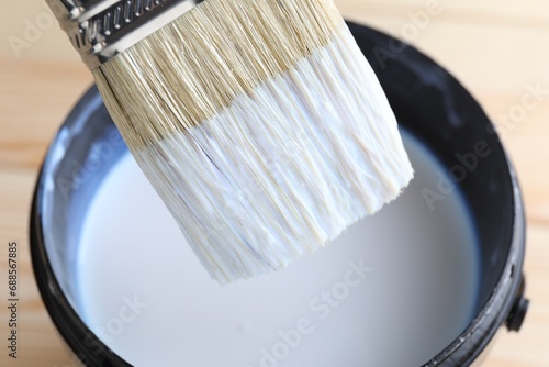 Dipping brush into can with varnish on table, closeup