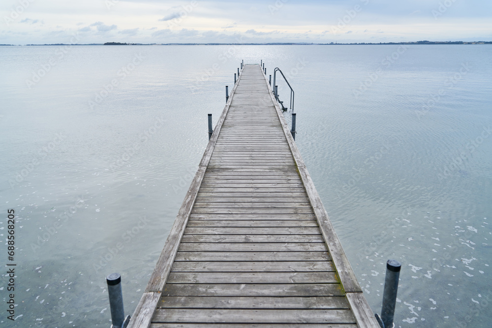Long wooden pier leading into water of lake in Sweden