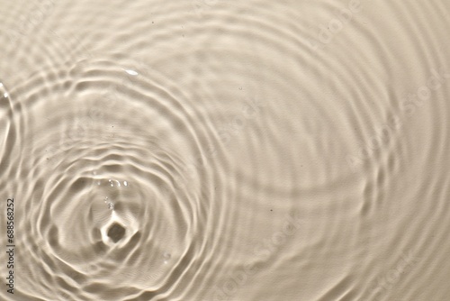 Rippled surface of clear water on beige background, top view