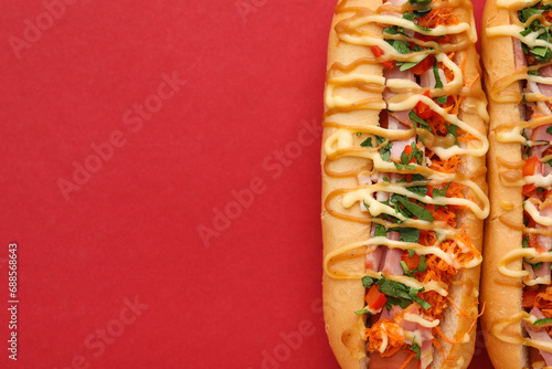 Delicious hot dogs with bacon, carrot and parsley on red background, top view. Space for text