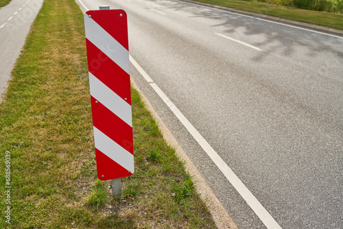 Red and white striped traffic sign on road as safety warning