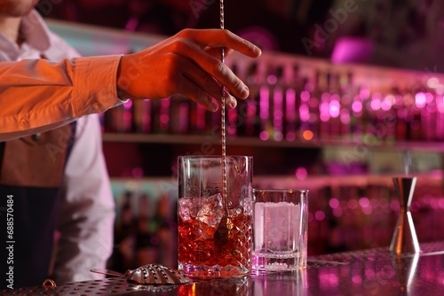 Bartender making fresh alcoholic cocktail at counter in bar, closeup photo