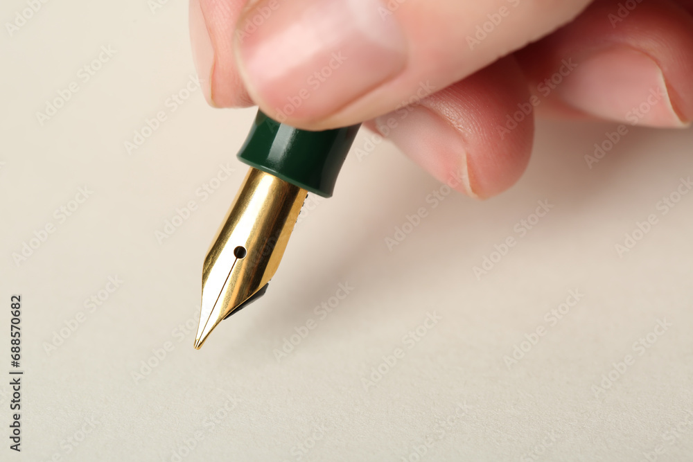 Woman with fountain pen above light paper, closeup Woman with fountain pen above light paper, closeup