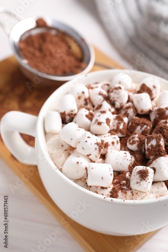 Cup of aromatic hot chocolate with marshmallows and cocoa powder on table, closeup