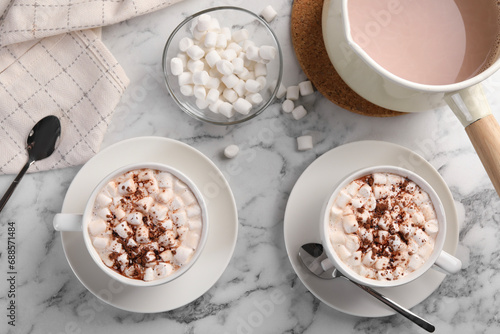 Aromatic hot chocolate with marshmallows and cocoa powder served on white marble table, flat lay
