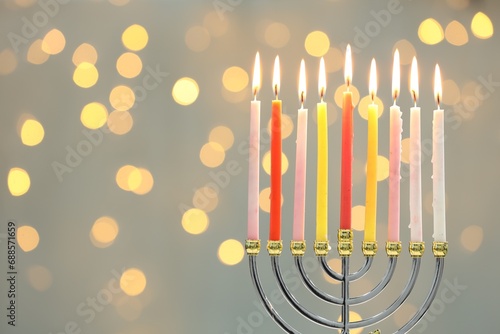 Hanukkah celebration. Menorah with burning candles against blurred lights, space for text