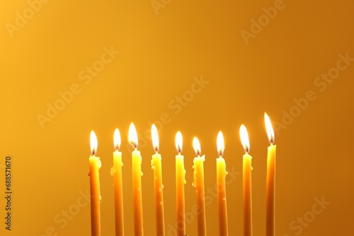 Hanukkah celebration. Burning candles on yellow background