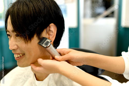 バリカンで男性客の髪を剃る美容師