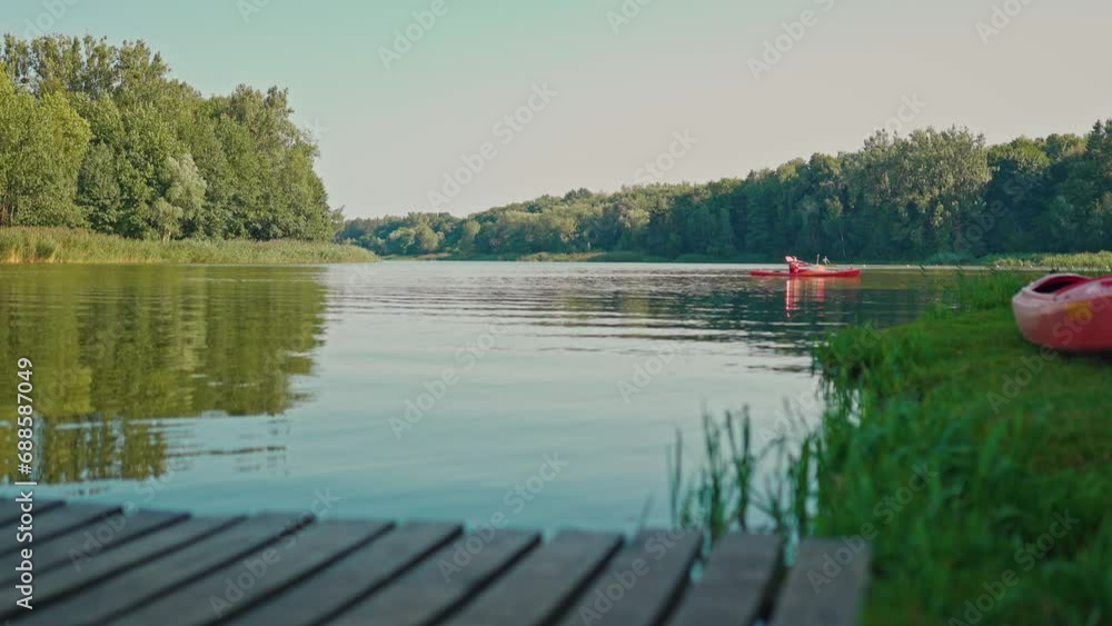 View of person paddling canoe or kayak on river. Canoeing in middle of pond or lake. Human in boat floating on water. Beautiful nature. Landscape. Aquatic sports. Activities concept. View of person paddling canoe or kayak on river. Canoeing in middle of pond or lake. Human in boat floating on water. Beautiful nature. Landscape. Aquatic sports. Activities concept.