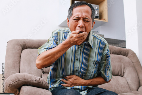 Asian senior man having stomachache, food poisoning have a bacteria infection. Unhealthy elderly painful on stomach vomit. photo