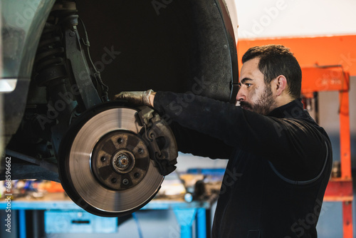 Mechanic fixing the brakes of a car in his workshop.