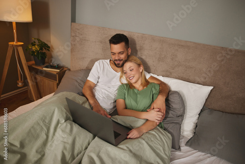 Young couple with laptop in the bed