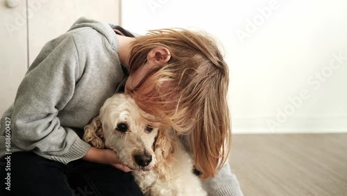 In the cozy confines of home, a young lad lovingly pets his Royal Poodle, the dog reveling in the attention and reciprocating the affection with a wagging tail photo