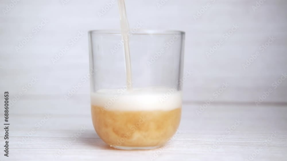 Pouring beer into a glass against a light background, capturing the golden liquid as it cascades, promising a moment of pure refreshment Pouring beer into a glass against a light background, capturing the golden liquid as it cascades, promising a moment of pure refreshment