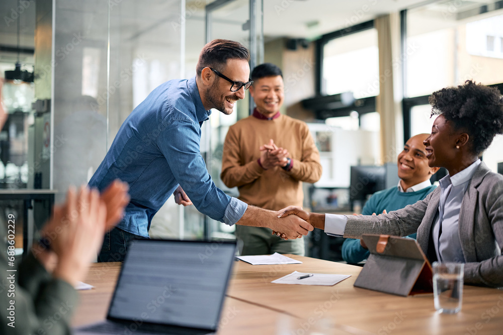 Happy CEO handshaking with black female colleague during business meeting in office. Happy CEO handshaking with black female colleague during business meeting in office.