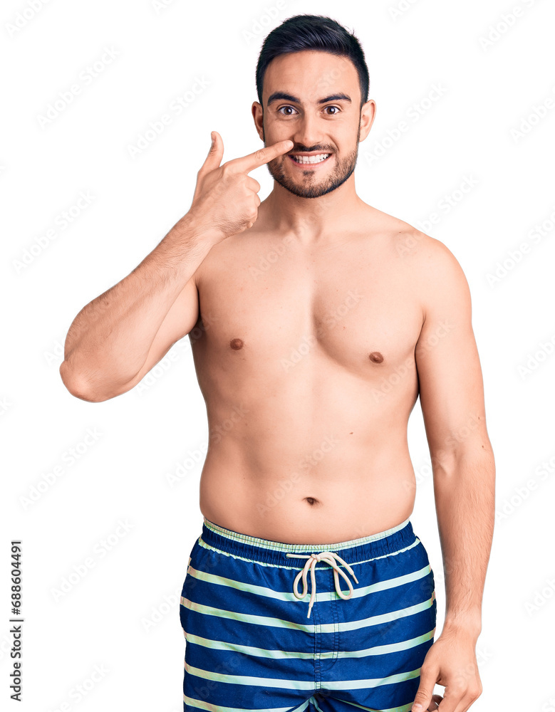 Fototapeta premium Young handsome man wearing swimwear pointing with hand finger to face and nose, smiling cheerful. beauty concept