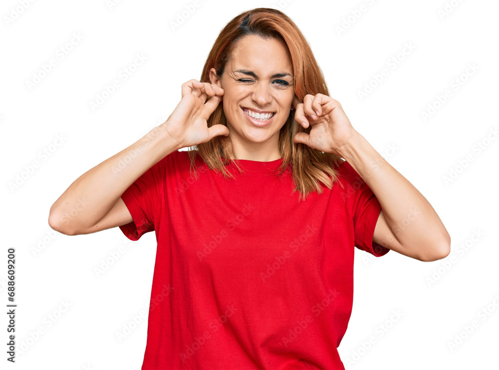 Hispanic young woman wearing casual red t shirt covering ears with fingers with annoyed expression for the noise of loud music. deaf concept. Hispanic young woman wearing casual red t shirt covering ears with fingers with annoyed expression for the noise of loud music. deaf concept.