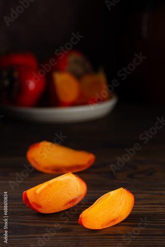 Fresh persimmons cut into slices on a wooden table. Healthy food, diet.