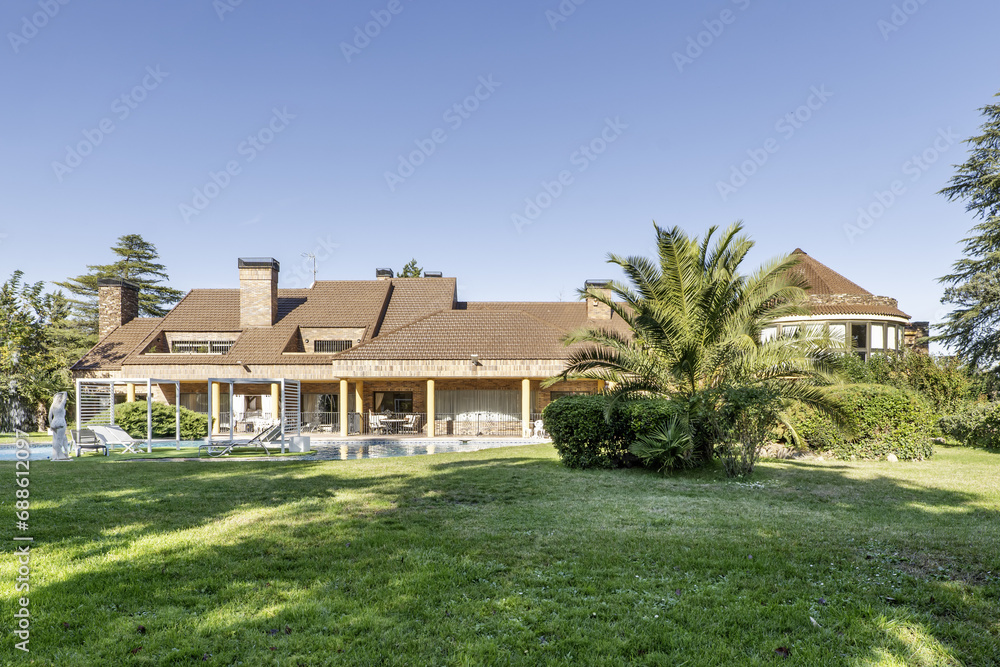 Rear facade of a luxury detached house with a swimming pool and a large garden with hedges, palm trees, statues and lots of grass Rear facade of a luxury detached house with a swimming pool and a large garden with hedges, palm trees, statues and lots of grass