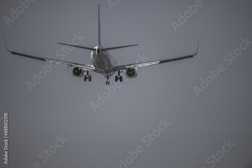 Tail of a commercial airplane descending to land on a gray day